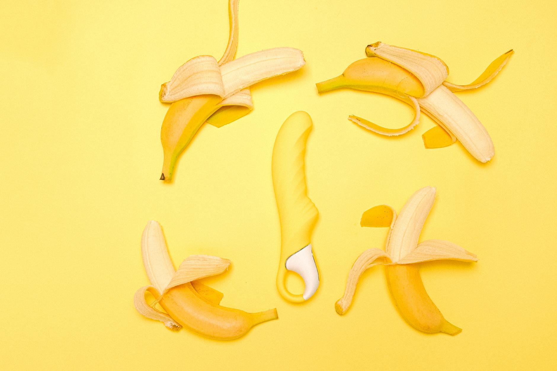 Vibrador de limão amarelo brilhante ao lado de limões descascados sobre fundo amarelo