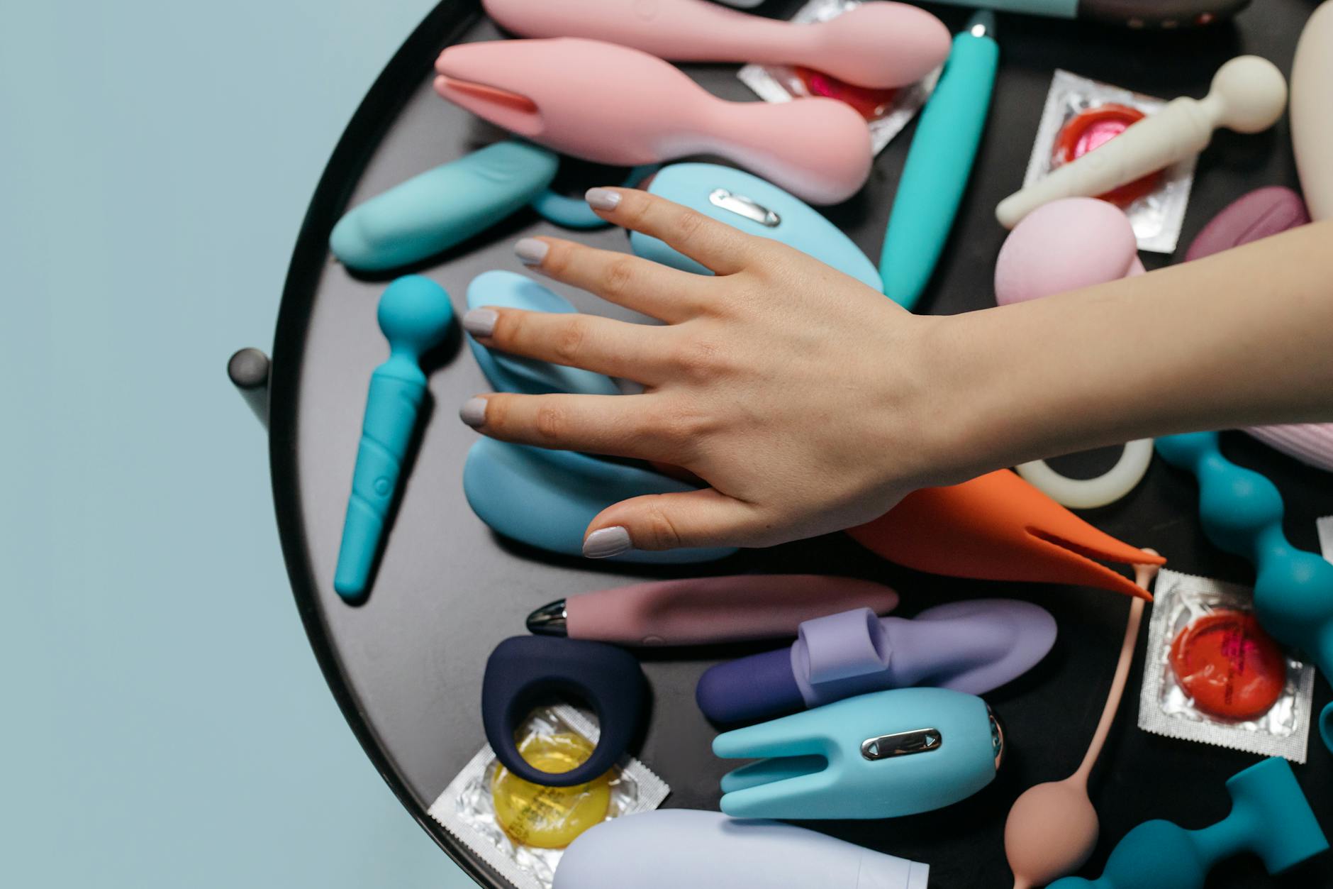 Uma mão com unhas brancas segurando um limão fresco em fundo rosa suave