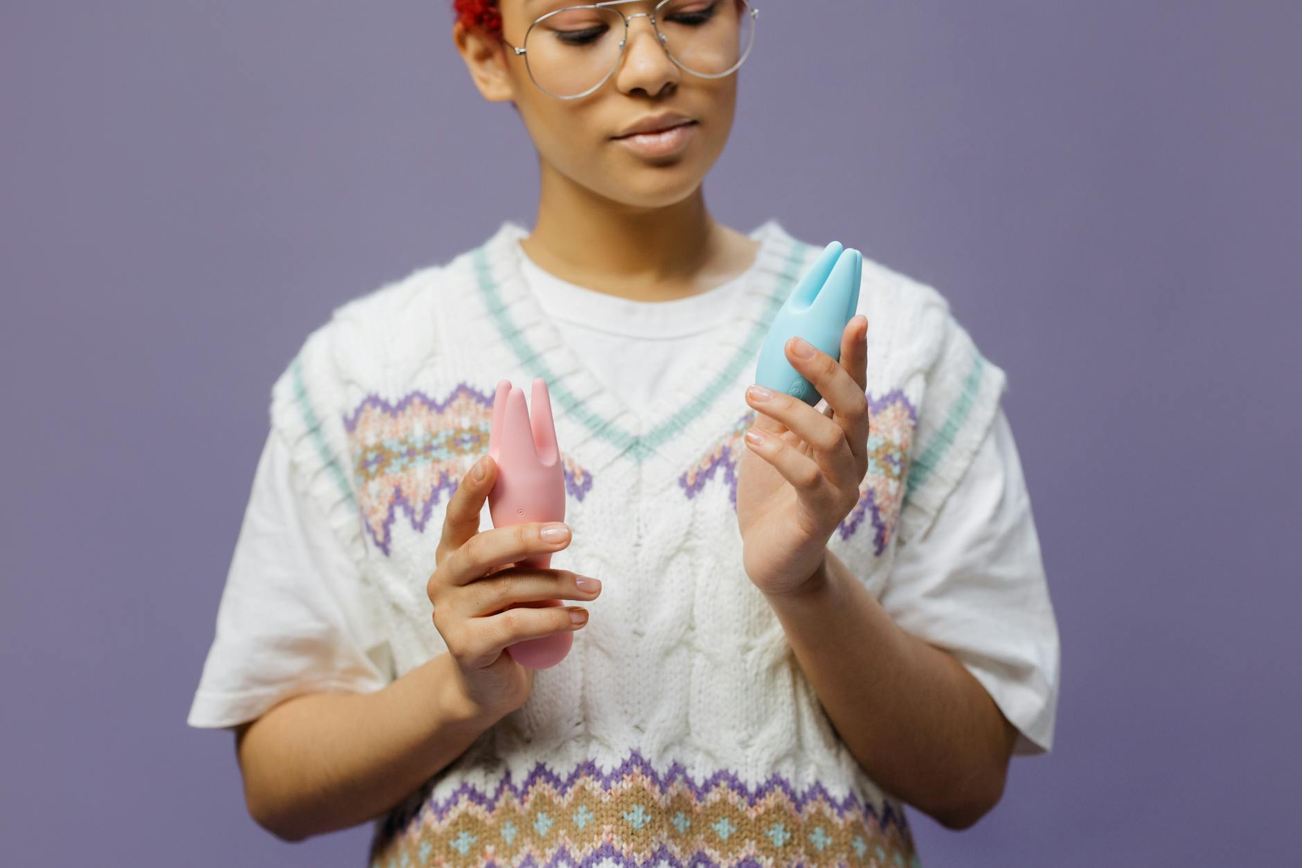 Mulher segurando vibradores silicone rosa e azul de forma contemplativa