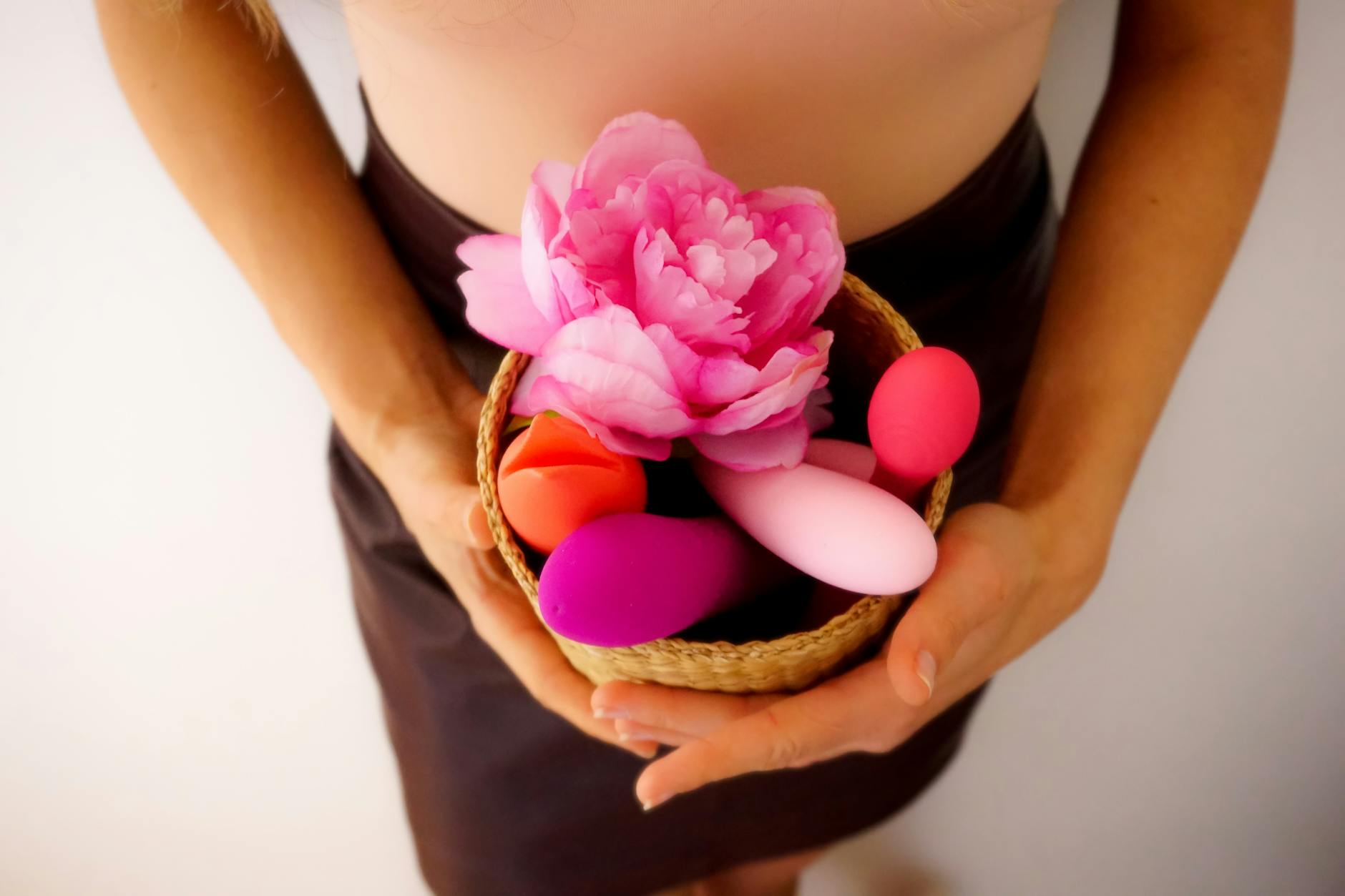 Vibrador azul cercado por flores e fatias de laranja em fundo amarelo
